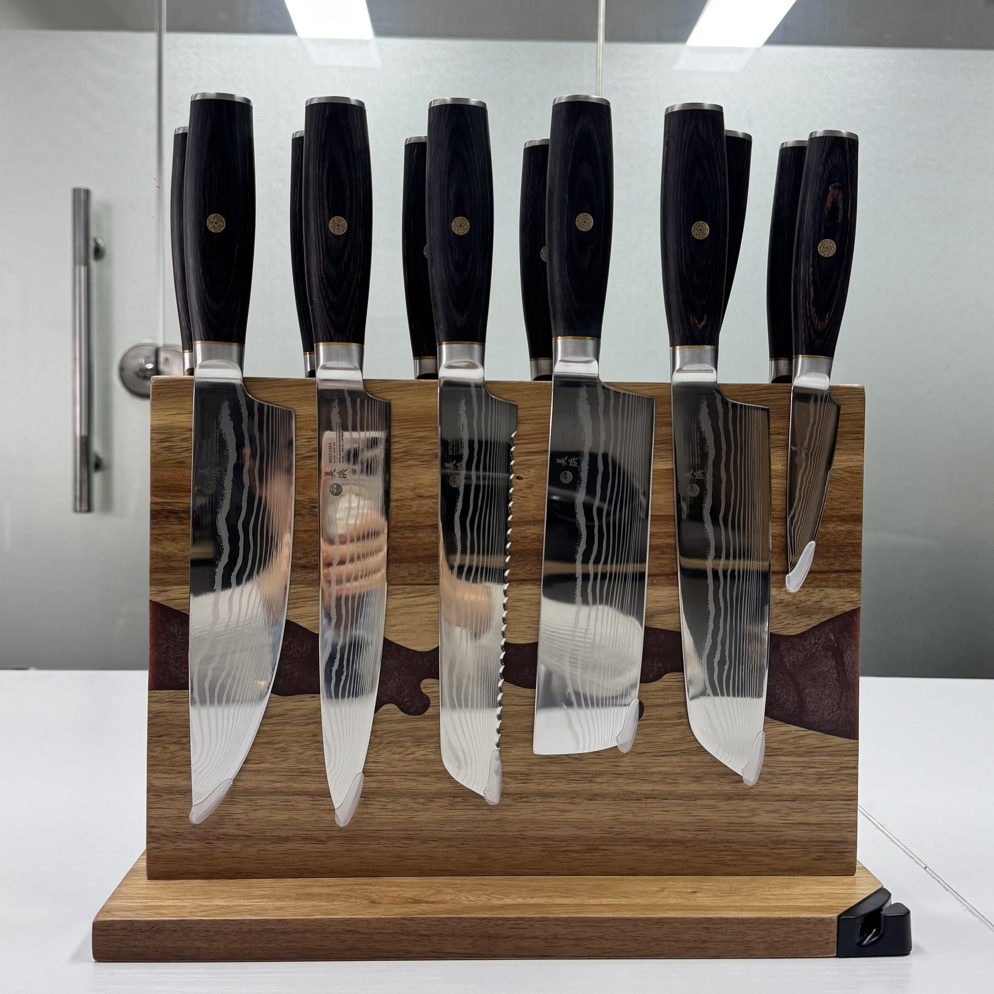 Six knives held on the magnetic stand, the stone-vein inlay running through the wood